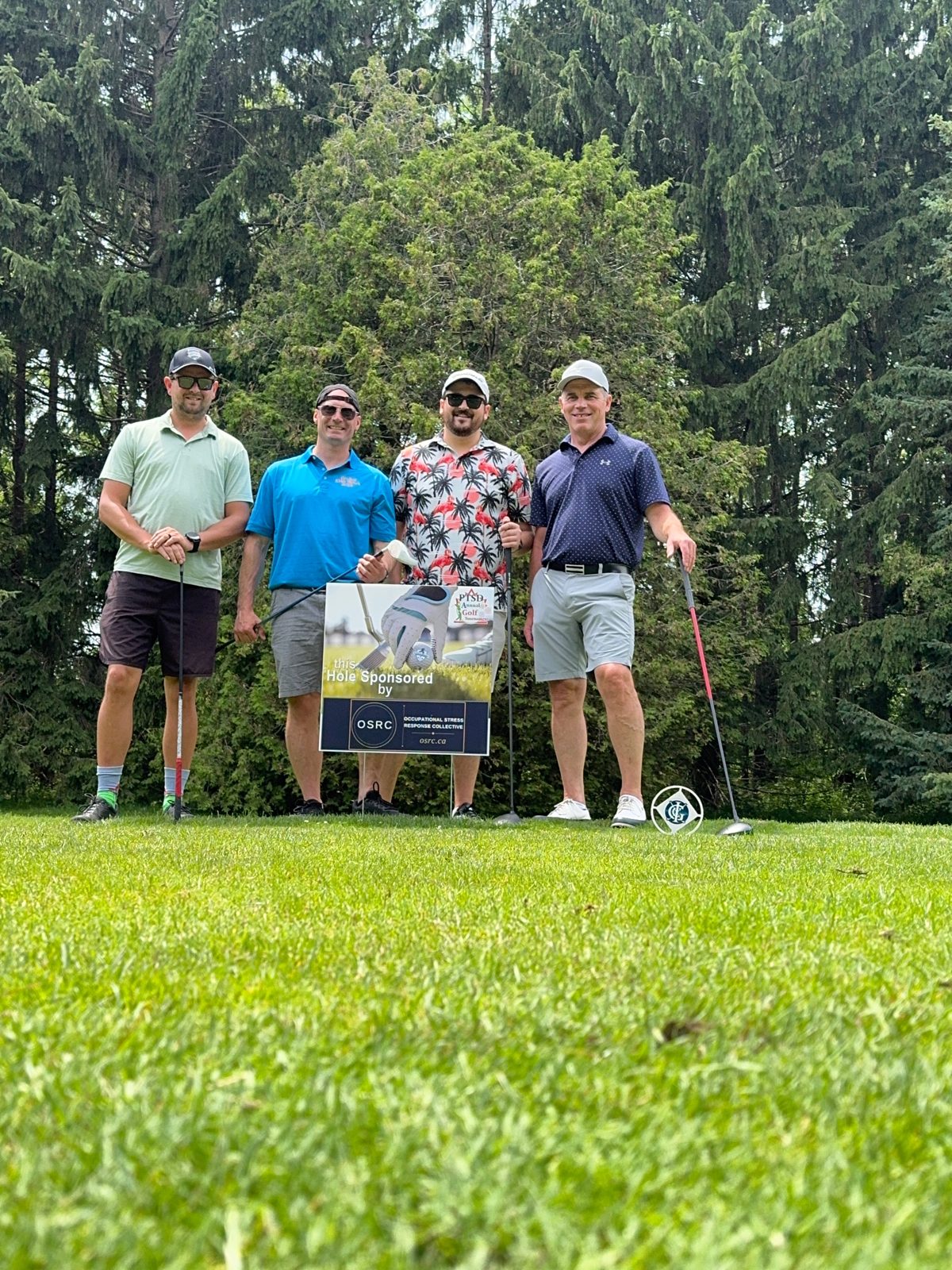 The OSRC foursome at the PTSD1REN annual golf tournament, standing at the tee box beside the OSRC hole sponsor sign.